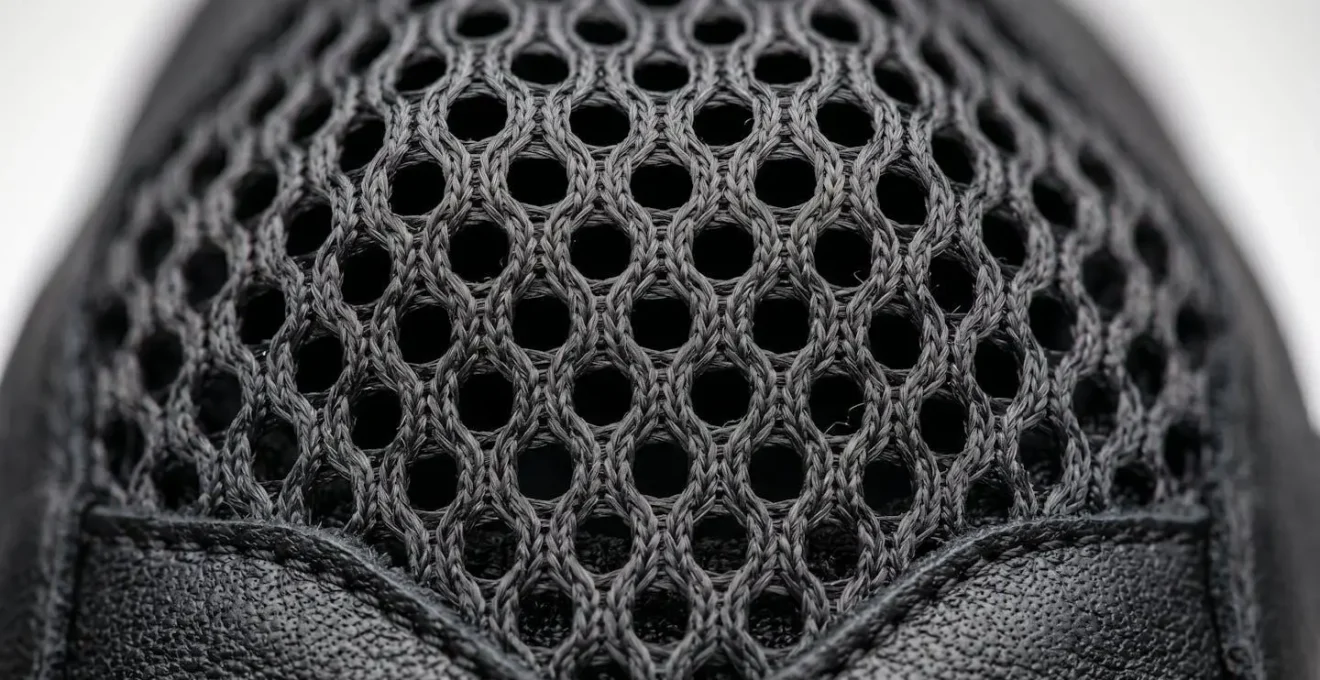 Détail macro des matériaux mesh techniques respirants d'un gant moto été