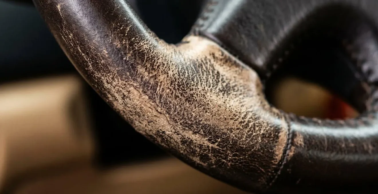 Détail macro de l'usure d'un volant de voiture révélant un kilométrage élevé